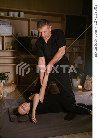 Girl in Thai massage session from therapist in massage room . Traditional Asian stretching therapy Girl in Thai massage session from therapist in massage room . Traditional Asian stretching therapy 127118305