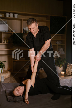 Girl in Thai massage session from therapist in massage room . Traditional Asian stretching therapy Girl in Thai massage session from therapist in massage room . Traditional Asian stretching therapy 127118307