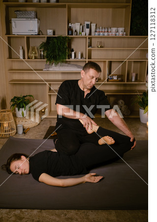 Male massage therapist performs back massage for pain treatment in spa. Thai massage with masseur in spa 127118312