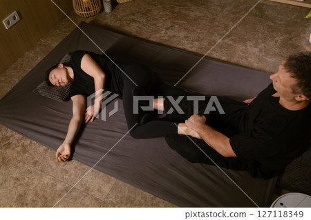 Professional masseur gives Girl Thai massage in massage parlor. Traditional Asian stretching therapy 127118349