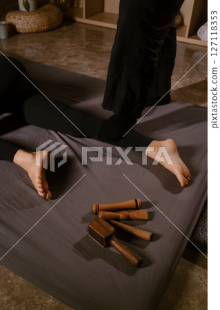 A man gives a relaxing Thai foot massage with a Tok-Sen massage kit at a beauty spa. Body care 127118353