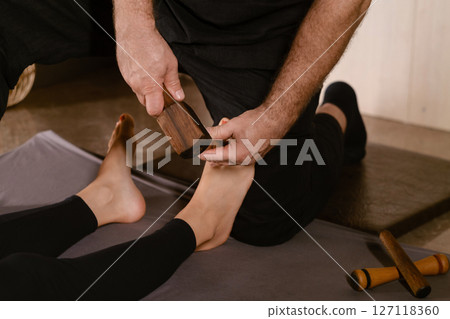 A man gives a relaxing Thai foot massage with a Tok-Sen massage kit at a beauty spa. Body care A man gives a relaxing Thai foot massage with a Tok-Sen massage kit at a beauty spa. Body care 127118360