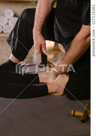 Massage therapist performs a relaxing Thai foot massage using a Tok-Sen massage set at the spa. Body care 127118361
