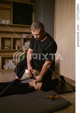 A man gives a relaxing Thai foot massage with a Tok-Sen massage kit at a beauty spa. Body care 127118363