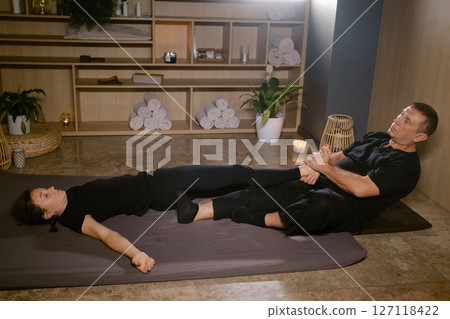 Girl in Thai massage session from therapist in massage room . Traditional Asian stretching therapy 127118422