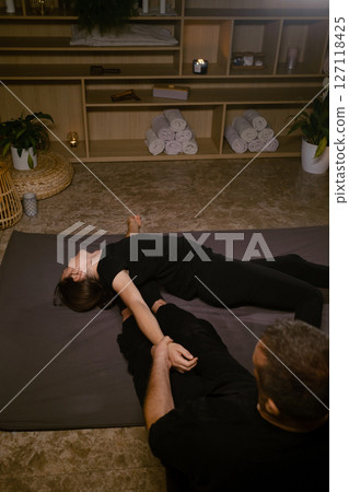 Girl in Thai massage session from therapist in massage room . Traditional Asian stretching therapy 127118425