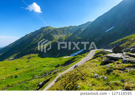 romania travel landscape with road in summer. beautiful mountain road that crosses southern carpathians. touristic destination of europe. sunny day with blue sky and fluffy clouds romania travel landscape with road in summer. beautiful mountain road that crosses southern carpathians. touristic destination of europe. sunny day with blue sky and fluffy clouds 127118595