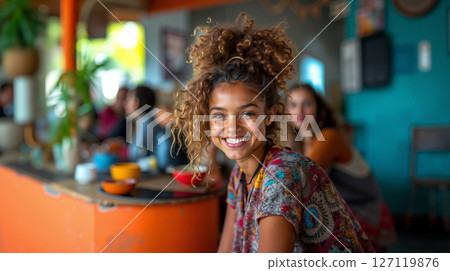 A woman with curly hair smiles at the camera 127119876