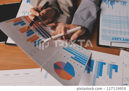 Group of confident business people point to graphs and charts to analyze market data, balance sheet, account, net profit to plan new sales strategies to increase production capacity. Group of confident business people point to graphs and charts to analyze market data, balance sheet, account, net profit to plan new sales strategies to increase production capacity. 127119958