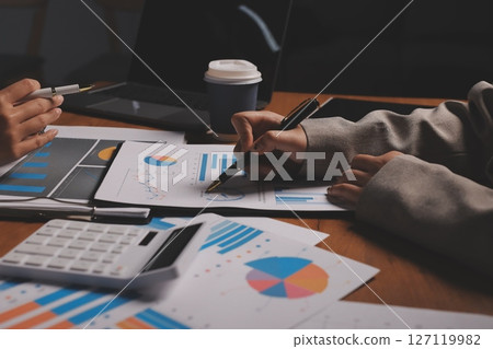 Group of confident business people point to graphs and charts to analyze market data, balance sheet, account, net profit to plan new sales strategies to increase production capacity. 127119982