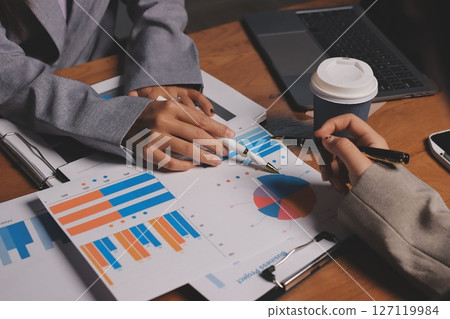 Group of confident business people point to graphs and charts to analyze market data, balance sheet, account, net profit to plan new sales strategies to increase production capacity. 127119984