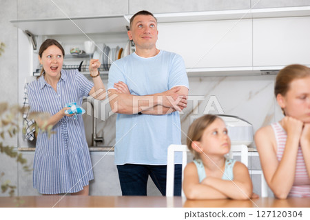 Parents quarrel behind back of blurred unrecognizable children daughters. 127120304