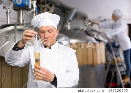 Portrait of expert who is checking beer in the laboratory of brew-house. 127120305