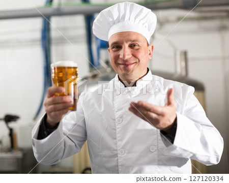 Cheerful man brewer presenting glass of beer 127120334