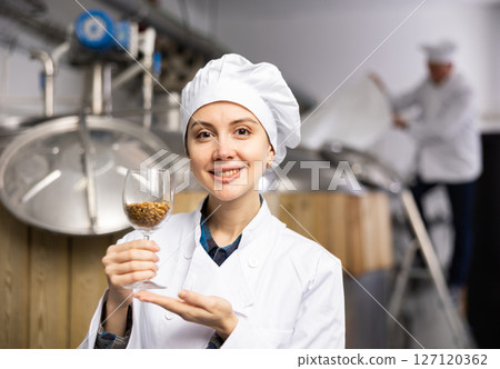 Portrait of positive female brewer with a glass of barley at brewery Portrait of positive female brewer with a glass of barley at brewery 127120362