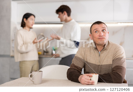 Dissatisfied man is tired of domestic quarrels. Young couple quarreling in background 127120406