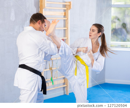 Adult man and young woman training karate kicks Adult man and young woman training karate kicks 127120504