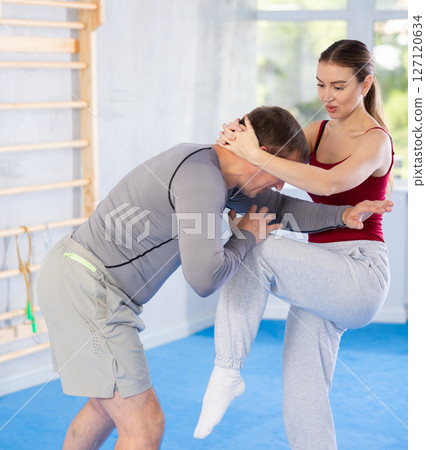 Young woman learns to fight back against an attacking man during self-defense training at gym Young woman learns to fight back against an attacking man during self-defense training at gym 127120634