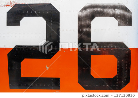 Black number -26- on an old aircraft fuselage with riveted panels 127120930