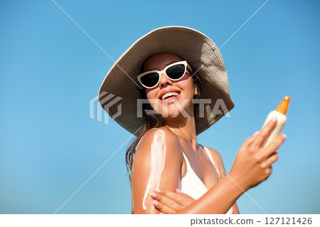 Beautiful Woman in Bikini Applying Sun Cream on Tanned Shoulder. Sun Protection. Skin and Body Care. Girl Using Sunscreen.  Portrait Of Female Holding Suntan Lotion or Moisturizing Sunblock. 127121426