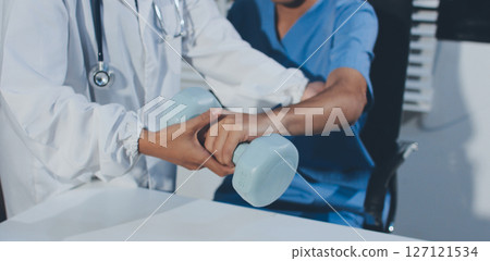 Person using hand weight with support of nurse Person using hand weight with support of nurse 127121534