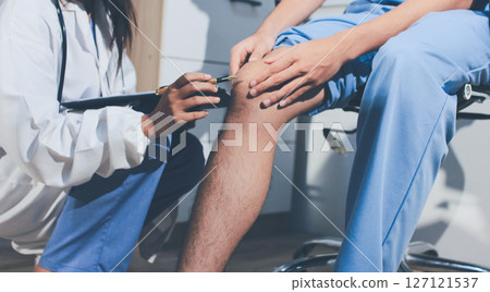 Physical therapist teaching a patient how to do exercises for his knee pain 127121537