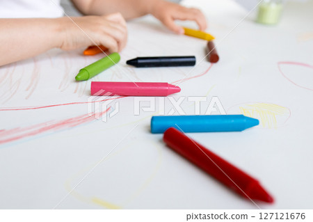 Child drawing with colorful crayons on white paper Child drawing with colorful crayons on white paper 127121676