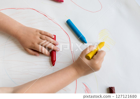 Child drawing with colorful crayons on white paper Child drawing with colorful crayons on white paper 127121680