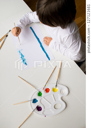 Young caucasian child painting with watercolors at home 127121681