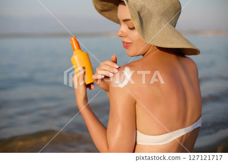 Sun cream on tanned shoulder with sun shape . Sun protection. Beautiful woman in bikini applying  Solar Cream. Skin and body care.Portrait of female holding suntan lotion 127121717