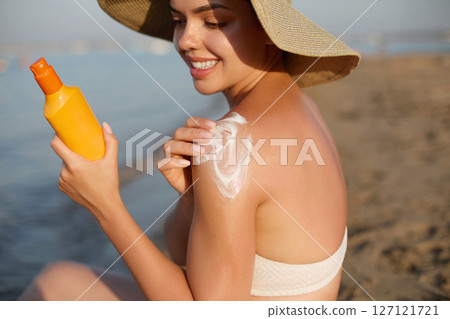 Sun cream on tanned shoulder with sun shape . Sun protection. Beautiful woman in bikini applying Solar Cream. Skin and body care.Portrait of female holding suntan lotion Sun cream on tanned shoulder with sun shape . Sun protection. Beautiful woman in bikini applying Solar Cream. Skin and body care.Portrait of female holding suntan lotion 127121721