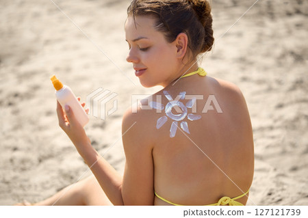 Sun cream on tanned shoulder with sun shape . Sun protection. Beautiful woman in bikini applying  Solar Cream. Skin and body care.Portrait of female holding suntan lotion 127121739