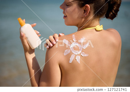 Sun cream on tanned shoulder with sun shape . Sun protection. Beautiful woman in bikini applying  Solar Cream. Skin and body care.Portrait of female holding suntan lotion 127121741