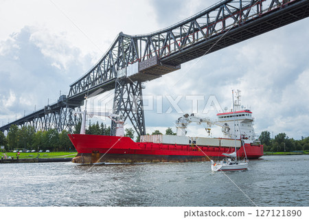 A cargo ship and a sailboat at the Rendsburg High Bridge on Kiel Canal A cargo ship and a sailboat at the Rendsburg High Bridge on Kiel Canal 127121890