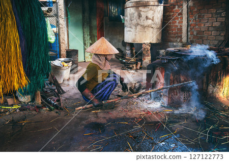 Vietnamese female worker in traditional straw hat works in reed dyeing workshop at woven mat factory in Vietnam. Woman does dirty hard men's work Vietnamese female worker in traditional straw hat works in reed dyeing workshop at woven mat factory in Vietnam. Woman does dirty hard men's work 127122773