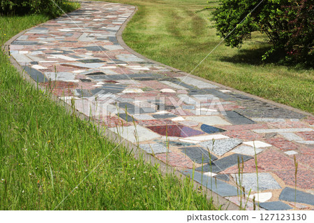 Path of colorful pieces of tiles in park. Green lawn and trees in summer on sunny day. Background for design. Ecology and nature. Landscape design. Path of colorful pieces of tiles in park. Green lawn and trees in summer on sunny day. Background for design. Ecology and nature. Landscape design. 127123130