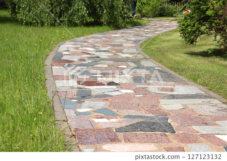 Path of colorful pieces of tiles in park. Green lawn and trees in summer on sunny day. Background for design. Ecology and nature. Landscape design. Path of colorful pieces of tiles in park. Green lawn and trees in summer on sunny day. Background for design. Ecology and nature. Landscape design. 127123132