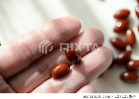 一位 50 多歲女性的指尖上，有兩顆胎盤補充劑藥丸 127123864