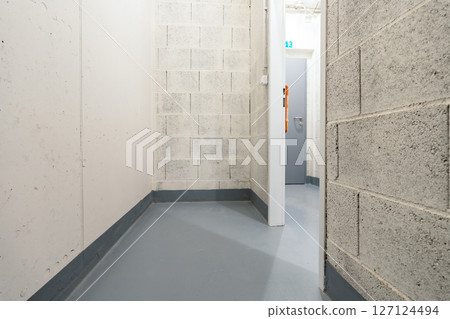 Small utility storage room with concrete walls and exit door in modern basement facility Small utility storage room with concrete walls and exit door in modern basement facility 127124494