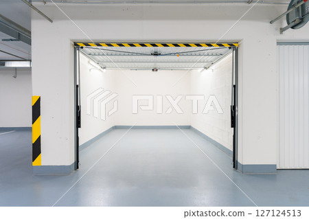 Clean, modern underground garage in a Czech apartment building with remote-controlled metal doors. 127124513