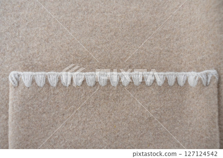 Decorative pocket stitching on beige wool blend coat close-up 127124542
