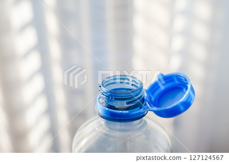 Innovative plastic bottle with attached blue cap for sustainable packaging, sunlight Innovative plastic bottle with attached blue cap for sustainable packaging, sunlight 127124567