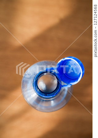 Open PET water bottle with attached blue cap for recycling and sustainability. 127124568