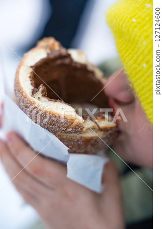 Child eating traditional Czech trdelnik with chocolate filling in winter. 127124600
