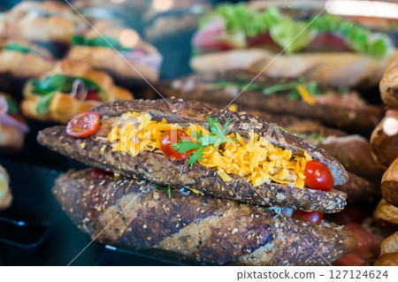 Fresh whole grain panini sandwich with cheddar cheese and cherry tomatoes in a bakery display. 127124624