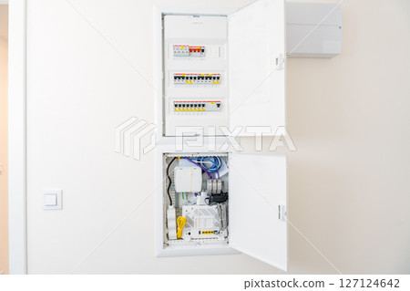 Modern electrical and network distribution panel with open doors in a smart home interior 127124642
