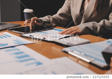 Group of confident business people point to graphs and charts to analyze market data, balance sheet, account, net profit to plan new sales strategies to increase production capacity. Group of confident business people point to graphs and charts to analyze market data, balance sheet, account, net profit to plan new sales strategies to increase production capacity. 127125035