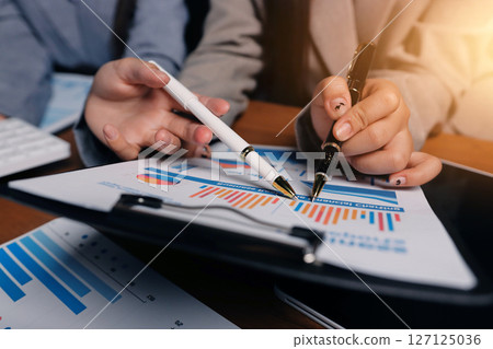 Group of confident business people point to graphs and charts to analyze market data, balance sheet, account, net profit to plan new sales strategies to increase production capacity. Group of confident business people point to graphs and charts to analyze market data, balance sheet, account, net profit to plan new sales strategies to increase production capacity. 127125036