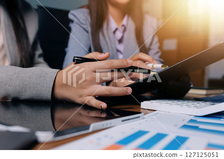 Group of confident business people point to graphs and charts to analyze market data, balance sheet, account, net profit to plan new sales strategies to increase production capacity. Group of confident business people point to graphs and charts to analyze market data, balance sheet, account, net profit to plan new sales strategies to increase production capacity. 127125051