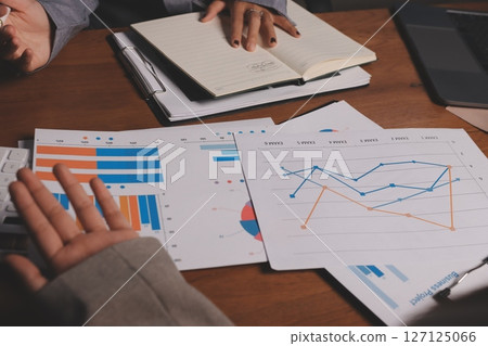 Group of confident business people point to graphs and charts to analyze market data, balance sheet, account, net profit to plan new sales strategies to increase production capacity. 127125066